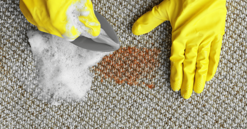 Man in yellow gloves cleans the carpet