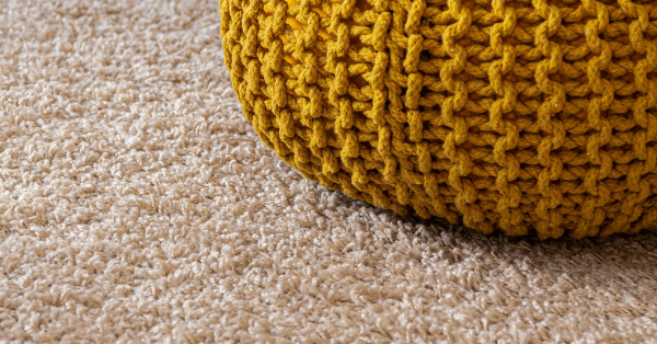 A ball of yarn on top of a wool carpet.