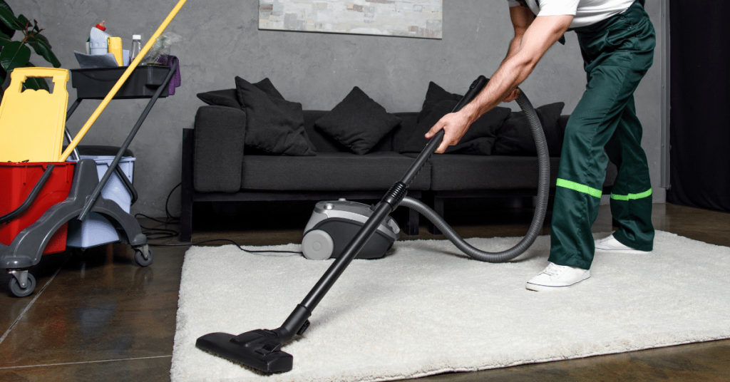 smiling young professional cleaner cleaning carpet